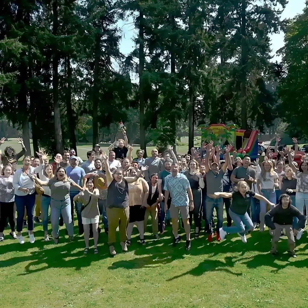 A large group of employees and founders jump in a field for a team portrait